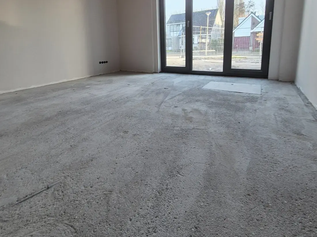 Lege kamer met een kale, vlakke dekvloer en een glazen pui over de volle hoogte