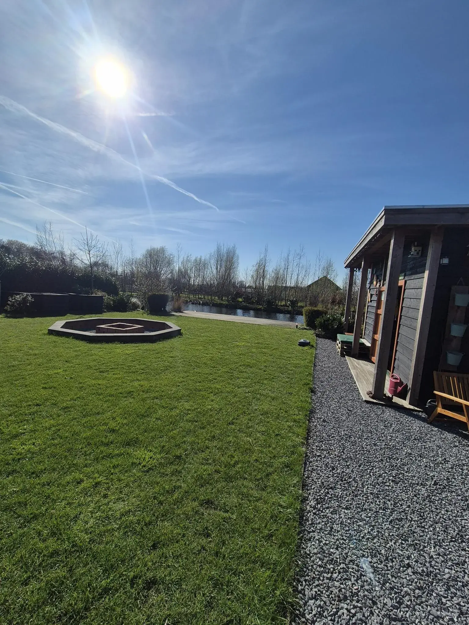 Gazon met vuurplaats, grindpad en tuinhuis